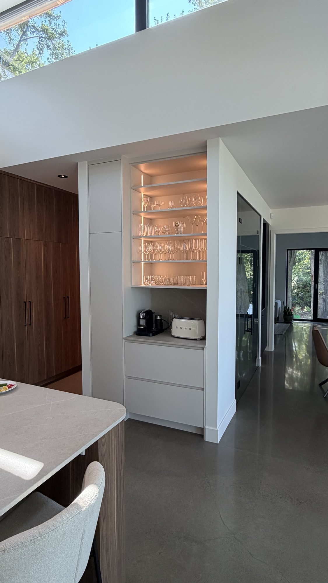 Built-in bar in the 30th Avenue Project — lit glass shelving for glassware, Silestone counter, built-in coffee machine and toaster.