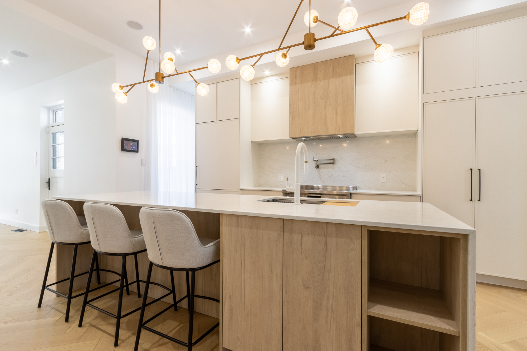 Detail of the oak-veneer hood and veined-marble backsplash, Atelier Pelissier custom kitchen.