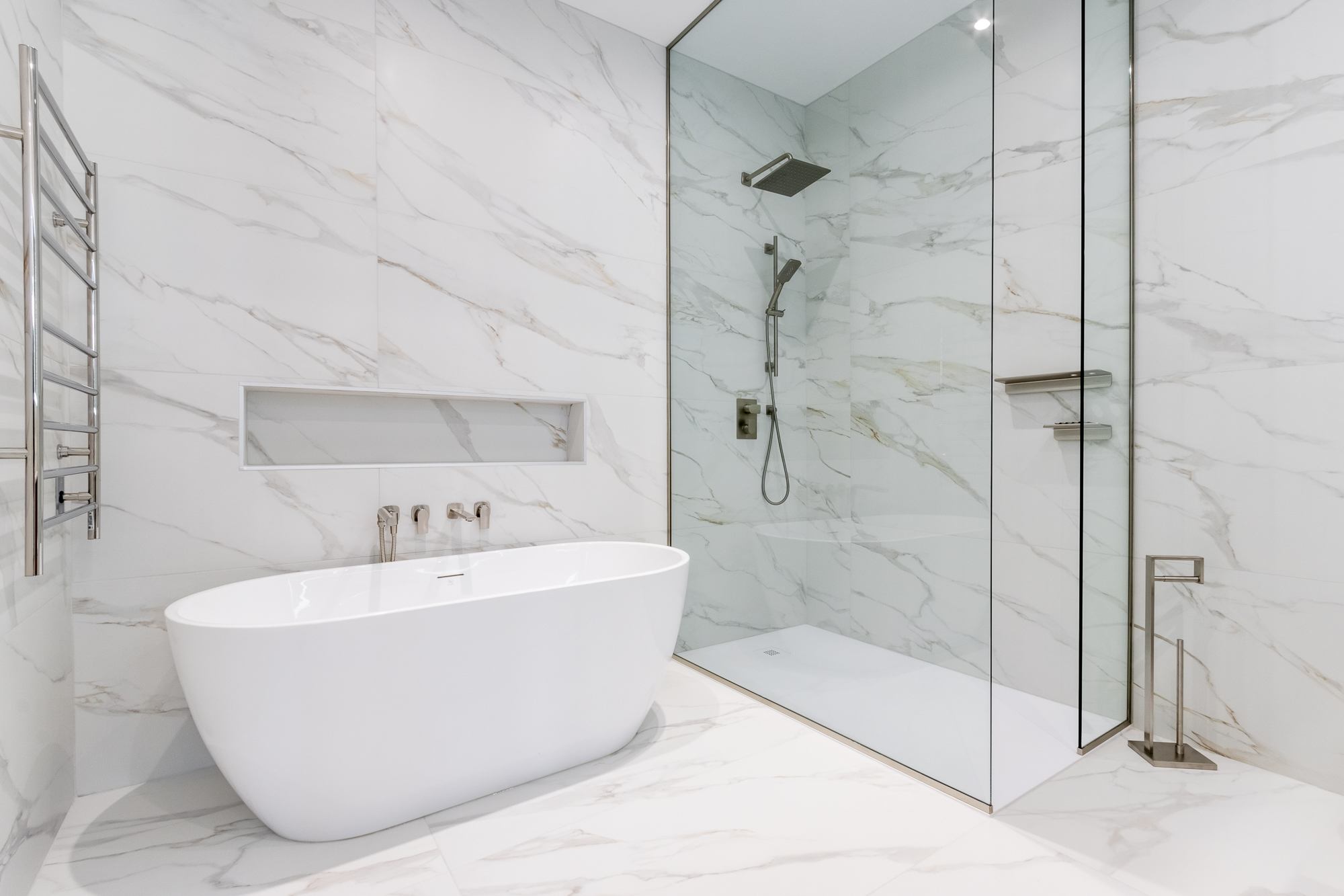 Westmount primary bathroom in full-height book-matched marble, freestanding tub and curbless Italian shower.